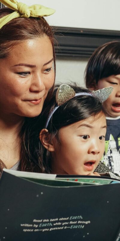 A joyful family bonding over a book at home, highlighting motherhood and togetherness.